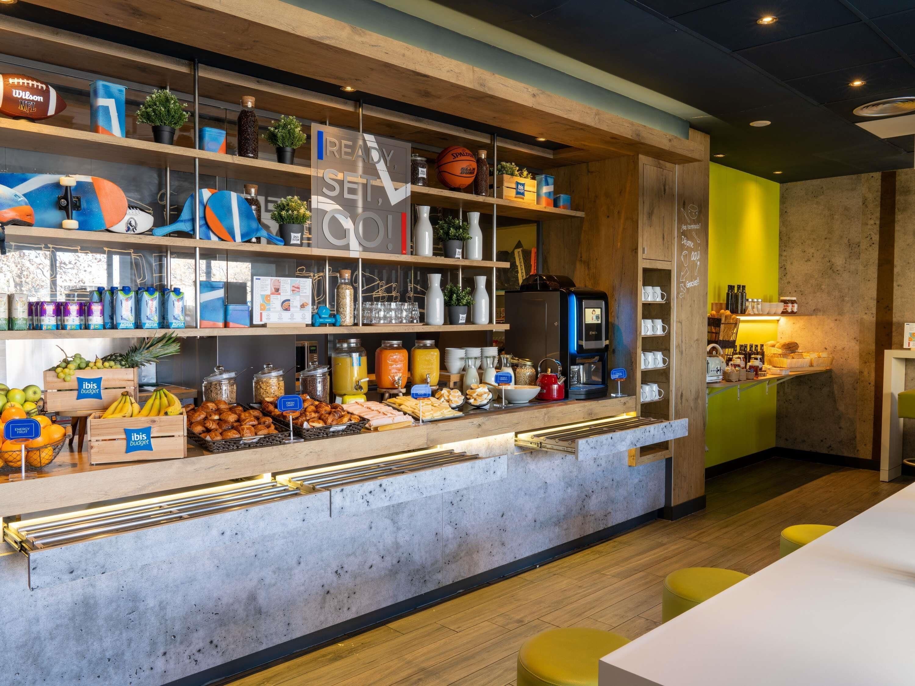 A breakfast bar with a coffee machine, fruit, and pastries.