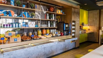 A breakfast bar with a coffee machine, fruit, and pastries.