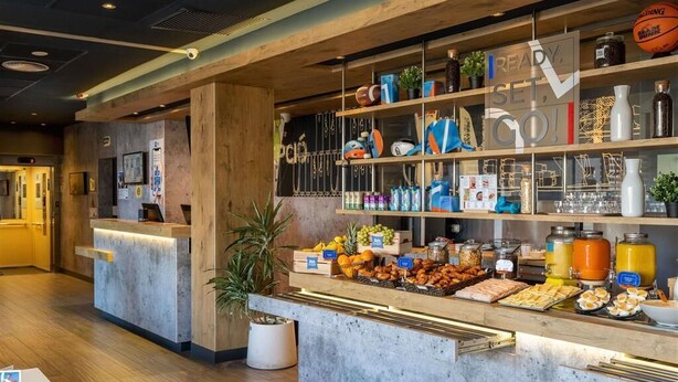 A reception area with a counter displaying various food items and a wooden interior. - ibis Budget Aeropuerto Barcelona Viladecans (Viladecans)