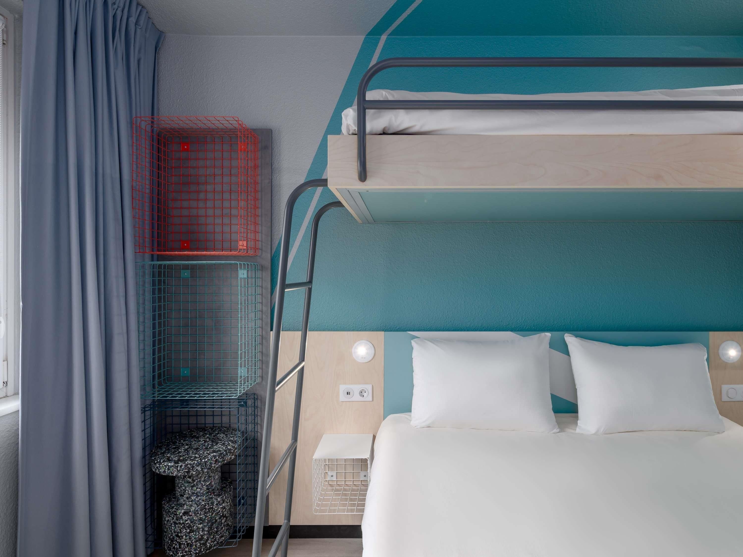 A bunk bed room with a window, curtains, and a small table.