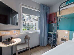 Une chambre d’hôtel comprenant un lit, un bureau avec un ordinateur portable, une chaise, une télévision, une fenêtre avec des rideaux et un balcon donnant sur une vue agréable.