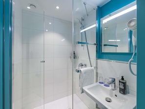 A modern bathroom with a glass shower enclosure, a white sink with a mirror, and a handheld showerhead. - Ibis Budget Hamburg St Pauli Messe (Hamburg)
