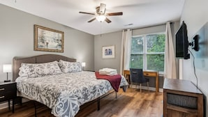 A bedroom with a bed, a desk, a chair, a ceiling fan, and a TV. - Sunny Retreat: Pool & Beach Near Condo (Wilmington)