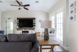 A living room with a sofa, a TV, a lamp, and a ceiling fan. - Delray Oasis: Pool, Gazebo & Beach Access (Delray Beach)