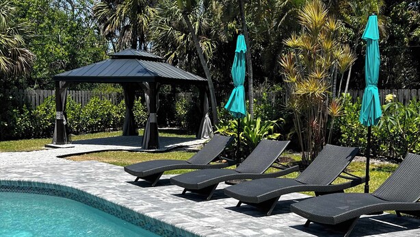 A pool area with lounge chairs, a gazebo, and a wooden fence. - Delray Oasis: Pool, Gazebo & Beach Access (Delray Beach)