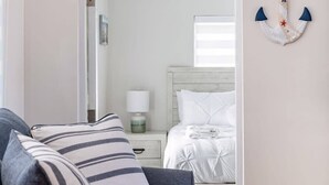 A room with a bed, a nightstand, a lamp, a sign above the door, and a wall-mounted anchor decoration. - Delray Oasis: Pool, Gazebo & Beach Access (Delray Beach)
