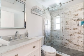 A modern bathroom with a marble sink, a large mirror, a glass-enclosed shower, and a toilet. - Delray Oasis: Pool, Gazebo & Beach Access (Delray Beach)