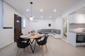 Cozinha moderna com armários brancos, forno embutido e área de refeições com mesa redonda e cadeiras pretas.