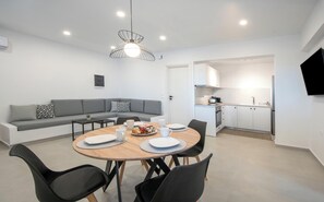 Um espaço de estar moderno com área de jantar, cozinha e sofá cinza com almofadas estampadas.