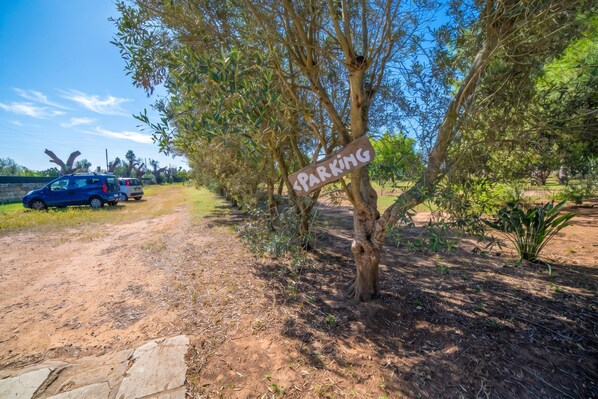 A parking area with a sign, a dirt path, and parked vehicles. - Masseria Le Palmentelle Pool And Garden (San Donato di Lecce)