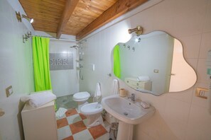 Uma casa de banho com chuveiro, sanita, bidé, lavatório e espelho.