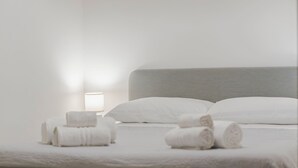 A neatly made bed with rolled towels and a bedside lamp. - Apartament Zio Michele Centro dell'Isola (Favignana)