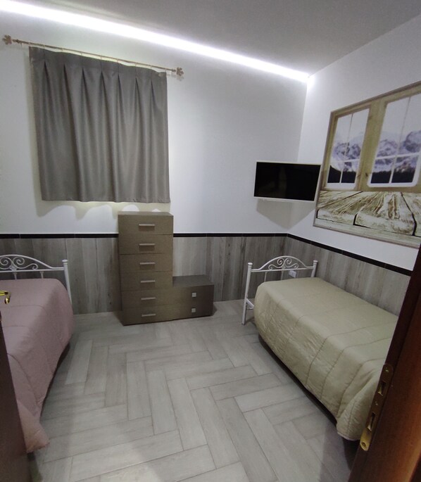 A bedroom with two beds, a dresser, a TV, and a window with curtains. - Re Sole Resort & spa (Grottaglie)