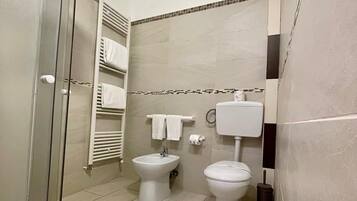 Ein modernes Badezimmer mit Duschkabine aus Glas, einem Bidet, einer Toilette und einem Handtuchhalter.