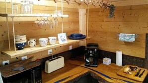 Une cuisine rustique avec des murs en bois, un plan de travail en bois, une machine à café, un grille-pain et divers ustensiles de cuisine.