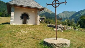 Une petite chapelle en pierre, dotée d’un clocher, entourée de montagnes.