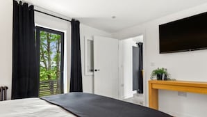 Un dormitorio con una cama, un televisor montado en la pared y un ventanal con cortinas.