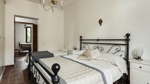 Een slaapkamer met een groot bed, een nachtkastje en een kroonluchter.