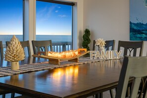 Une table à manger décorée de bougies, d’un centre de table composé de pommes de pin et d’une décoration portant l’inscription « FAMILLE ».