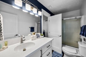 Une salle de bain moderne avec un lavabo blanc, un grand miroir et une douche à parois de verre.
