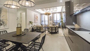 Una cocina moderna con comedor, que cuenta con una mesa grande, sillas negras y lámparas colgantes.