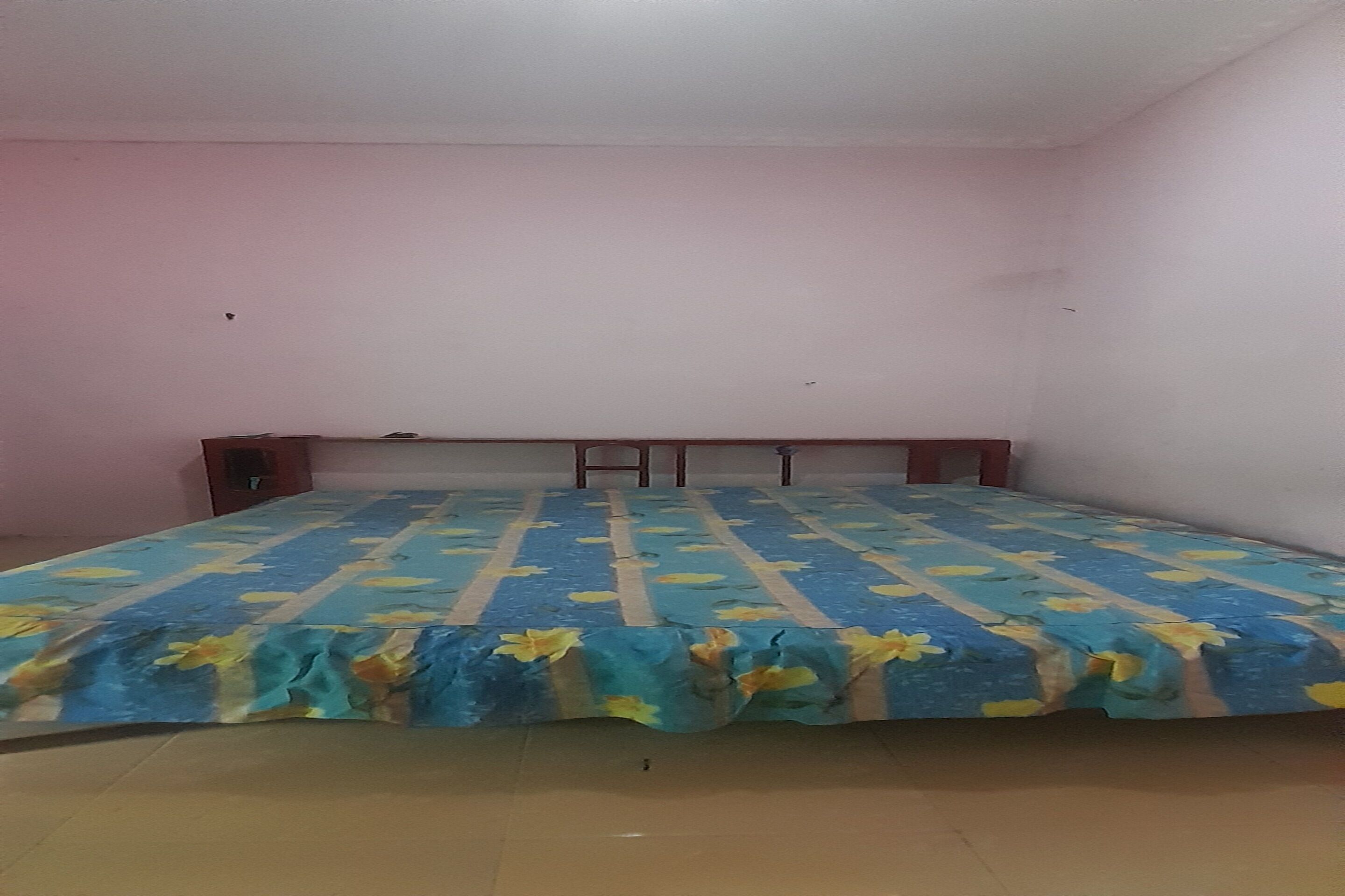A bedroom with a bed, a wooden headboard, and a tiled floor.