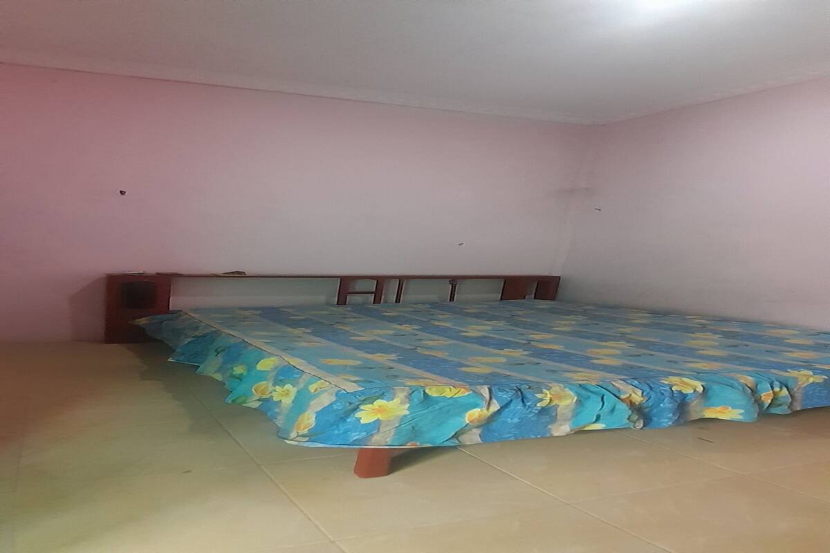 A room with a bed, a wooden headboard, and pink walls.