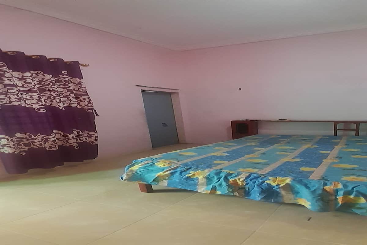 A bedroom with a bed, a door, and a curtain.