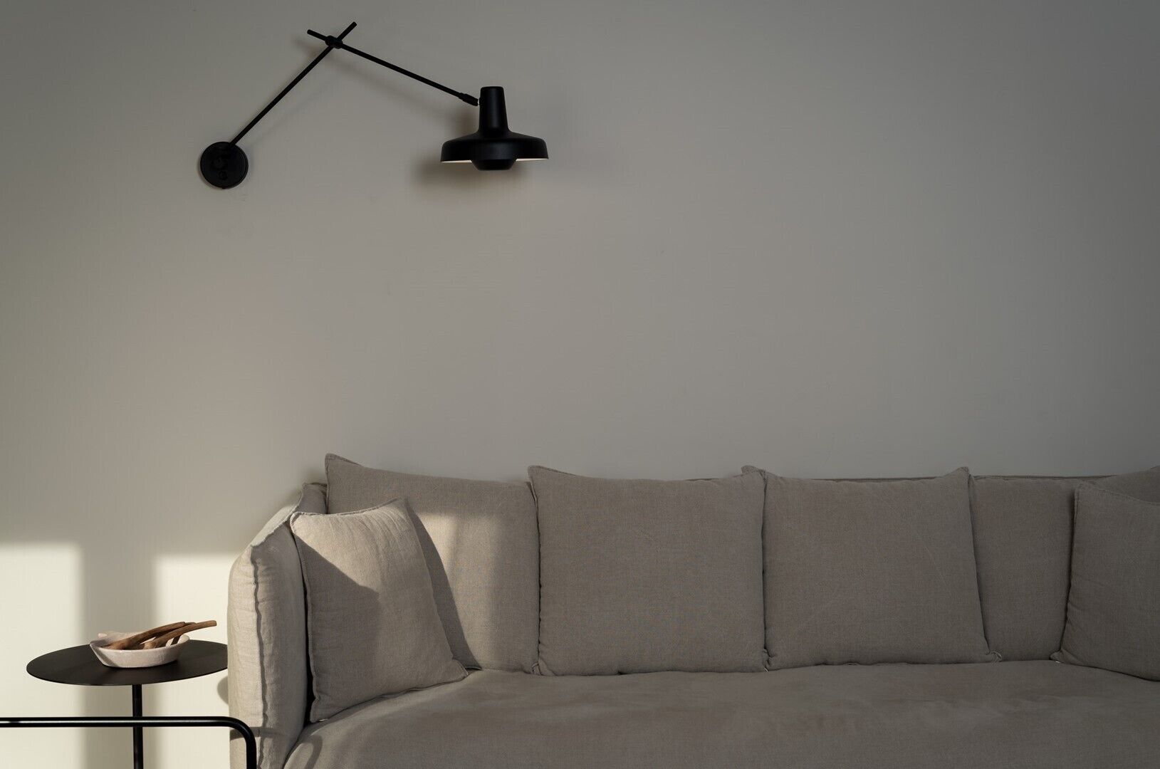 A minimalist living room with a grey sofa, a small round table, and a modern floor lamp.