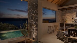 An outdoor patio with a stone wall, a pool, and a dining area with chairs and a table.