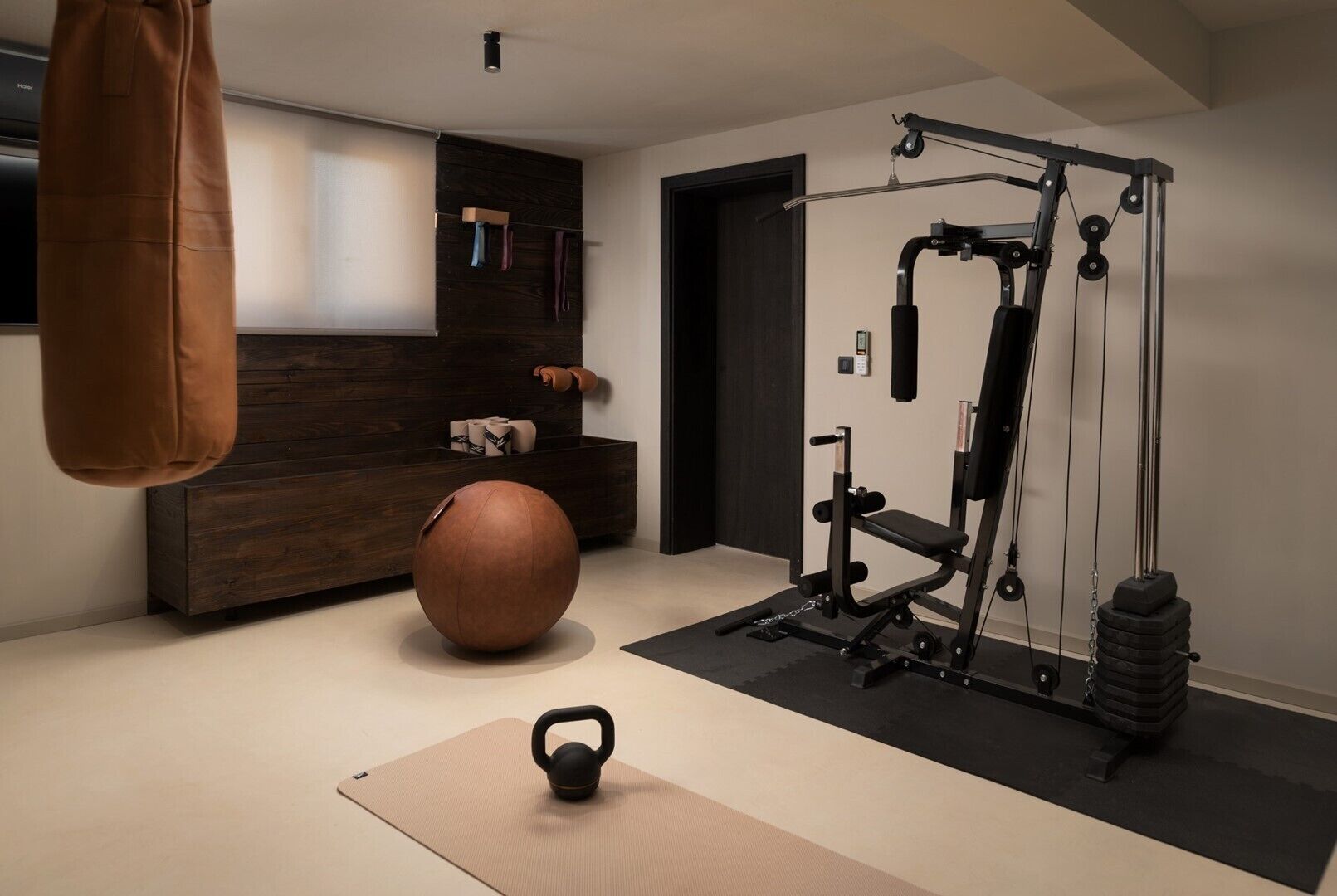 Une salle de sport à domicile équipée d’un kettlebell, d’un ballon lesté et d’un appareil à câbles.