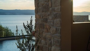 A stone wall with a view of a body of water and mountains in the distance.