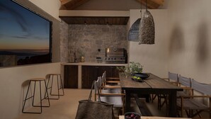 A cozy kitchen with a stone wall, wooden bar stools, and a dining table with chairs.