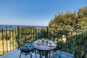Ein Balkon mit Tisch für zwei Personen, zwei Stühlen und Meerblick.