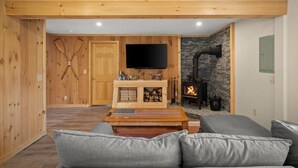Un salon chaleureux avec une cheminée, un téléviseur à écran plat et une table basse en bois.