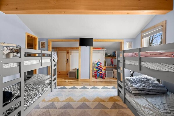 Une chambre avec des lits superposés, une télévision et un espace de jeux avec des jouets.