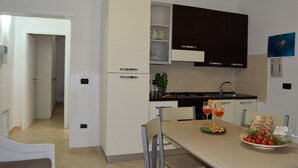 Une cuisine moderne avec un coin repas, comprenant un réfrigérateur, des placards et un évier.