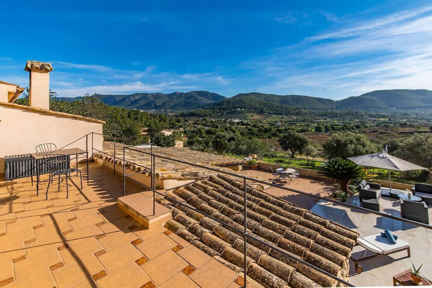 A rooftop terrace with stone steps, outdoor seating, and a view of the countryside.