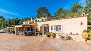 A Mediterranean-style building with a patio area, outdoor seating, and a stone facade. - Finca Andratx con Total Privacidad y Piscina (Andratx)