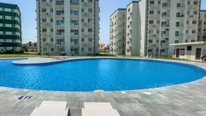 Une piscine dont la profondeur est indiquée à 1,20 mètre, entourée d’immeubles résidentiels à plusieurs étages.