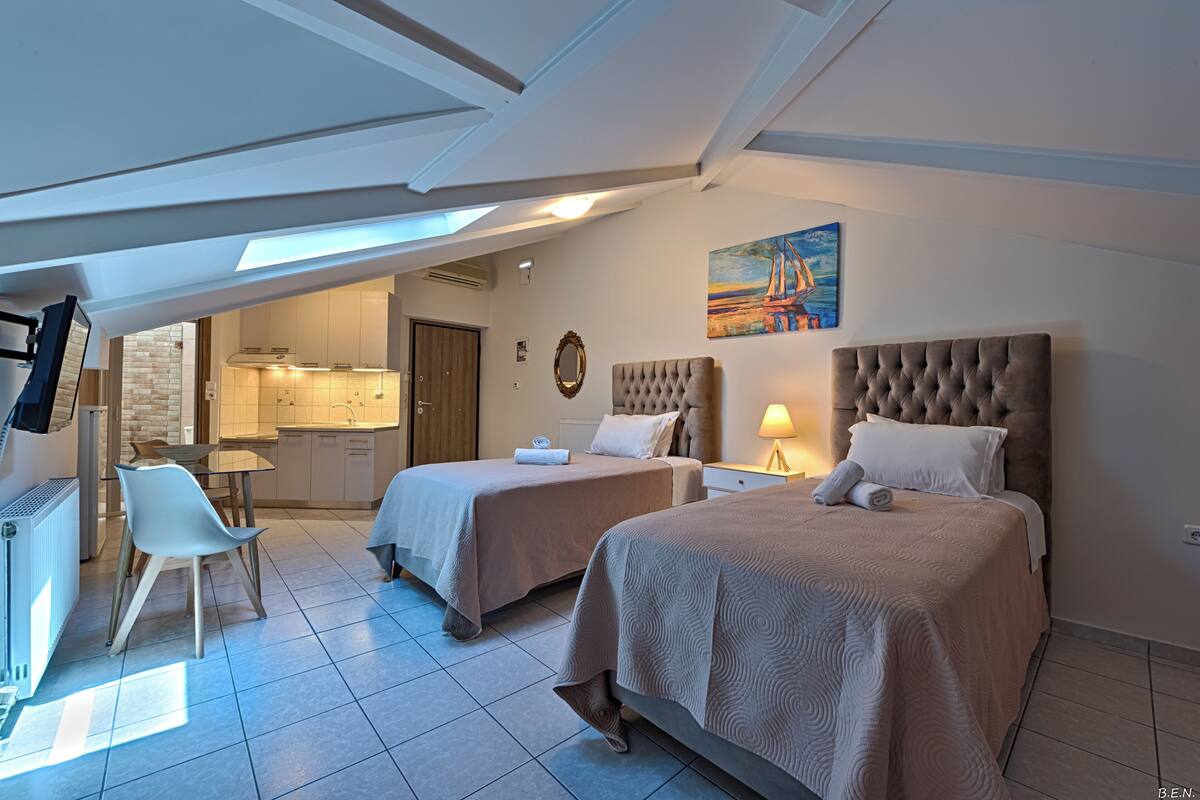 A hotel room with two beds, a dining area, and a kitchen.