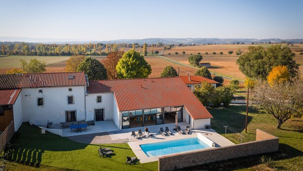 Una casa moderna con piscina, mobiliario exterior y vistas al campo.