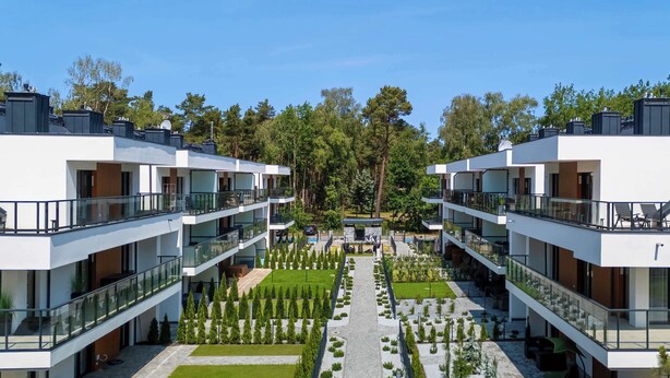 Un hotel moderno con edificios de dos pisos, un patio central con un sendero y follaje circundante.