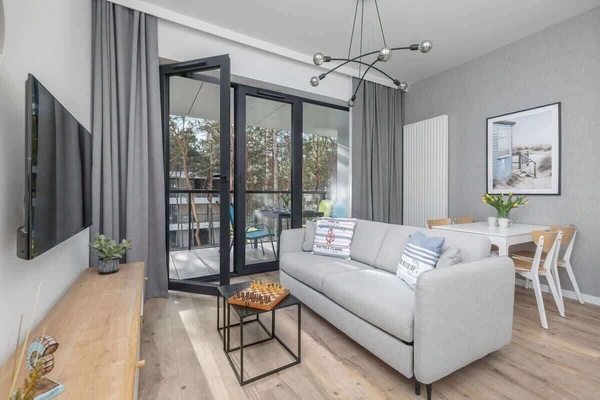 Living room with a comfortable sofa, wall-mounted TV, and a bright atmosphere.