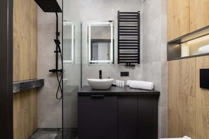 Bathroom features a glass-enclosed shower, vessel sink, and dark-toned vanity.