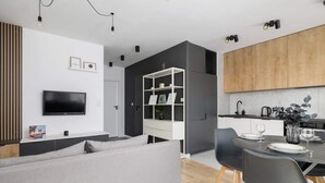 En moderne stue med en grå sofa, et fladskærms-tv monteret på væggen og et hvidt konsolbord.