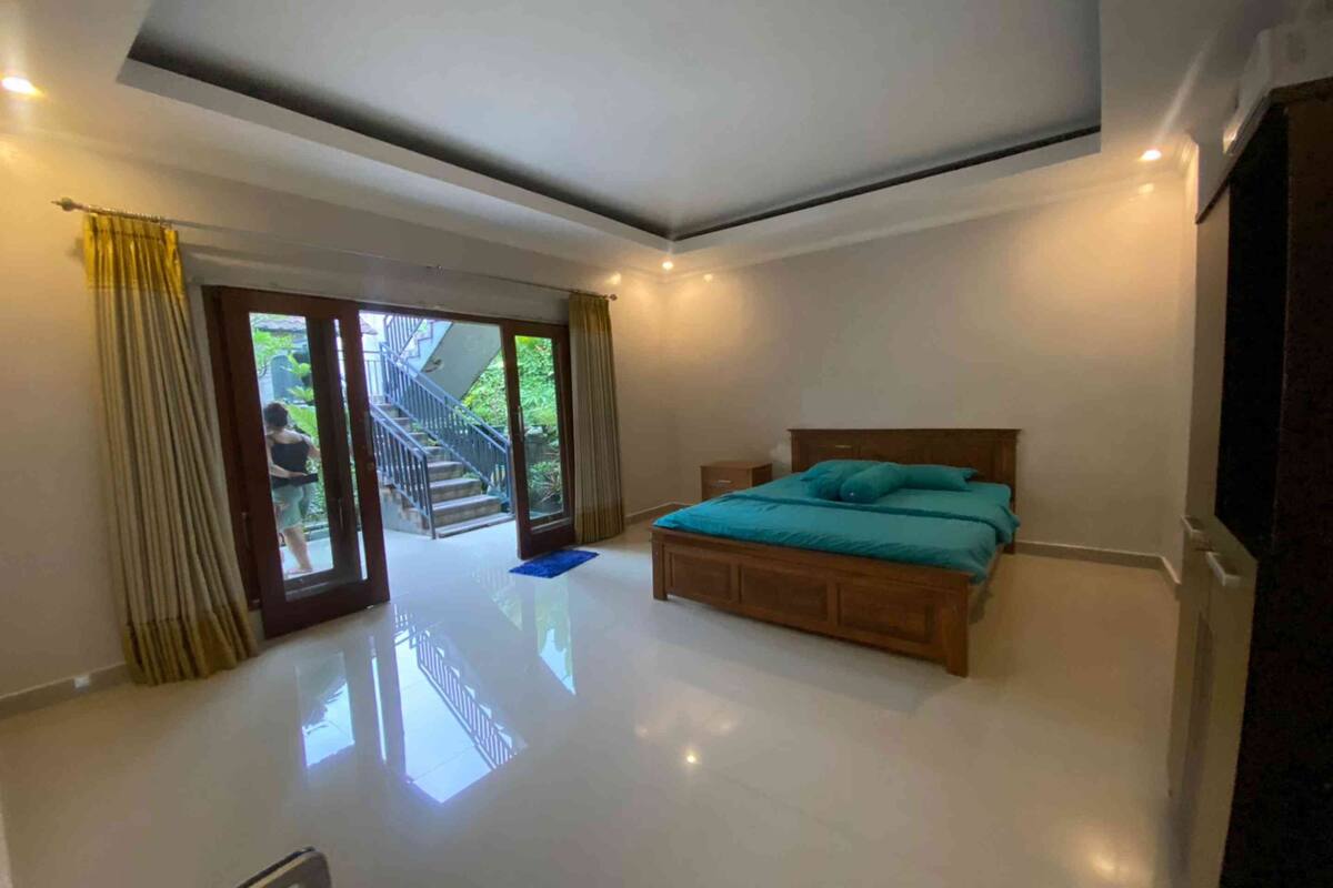 Ein Schlafzimmer mit einem großen Bett, einer Schiebetür zu einem Balkon und einem klaren, modernen Design.