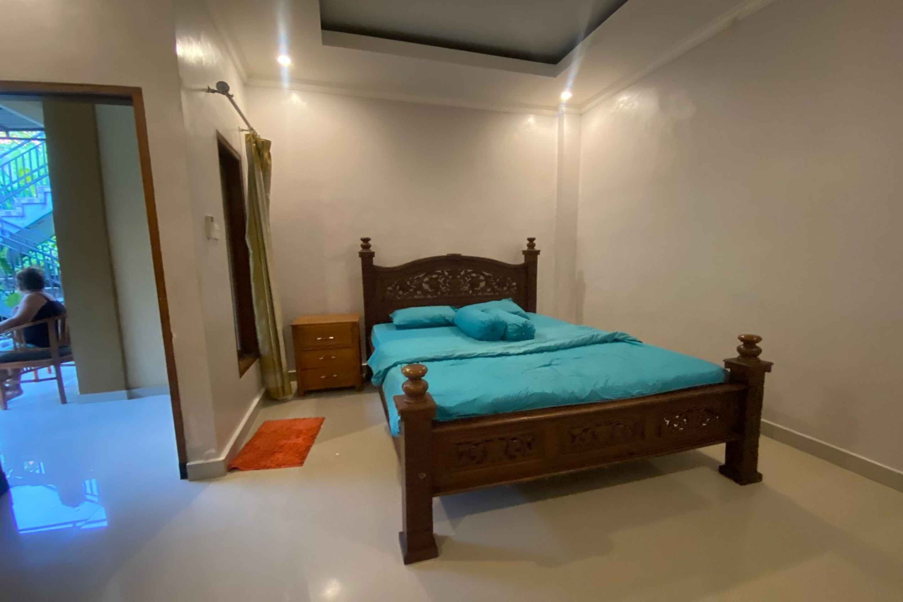 A bedroom with a wooden bed, a nightstand, and a window with curtains.