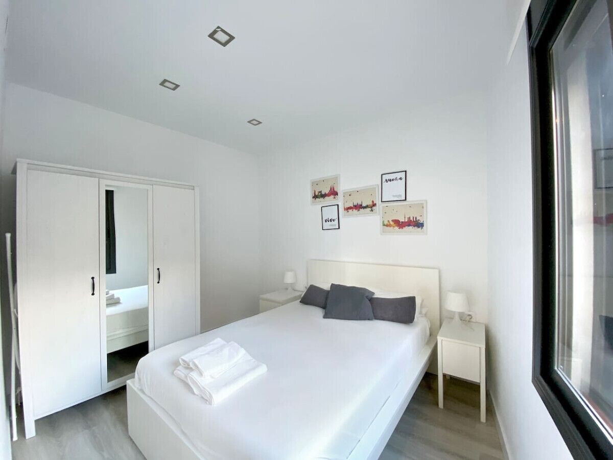 Camera da letto moderna con un ampio letto, un armadio, comodini e opere d'arte alle pareti.