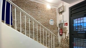 Una escalera con barandillas blancas que lleva a un cuarto con pared de ladrillo y una puerta negra.